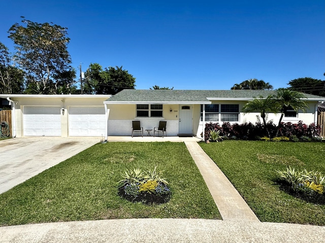 single story home with driveway, brick siding, an attached garage, a front yard, and stucco siding