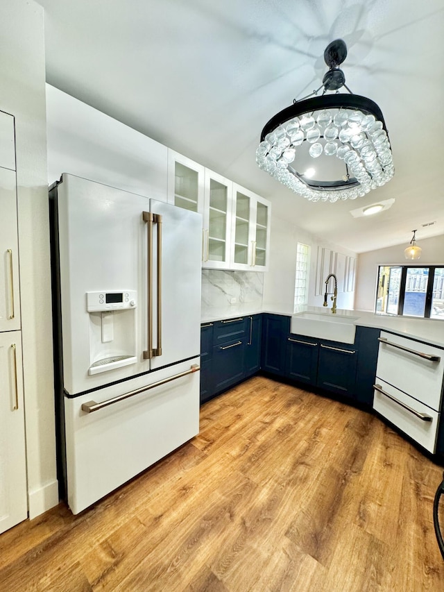 kitchen featuring blue cabinets, a sink, light countertops, high end white refrigerator, and light wood finished floors