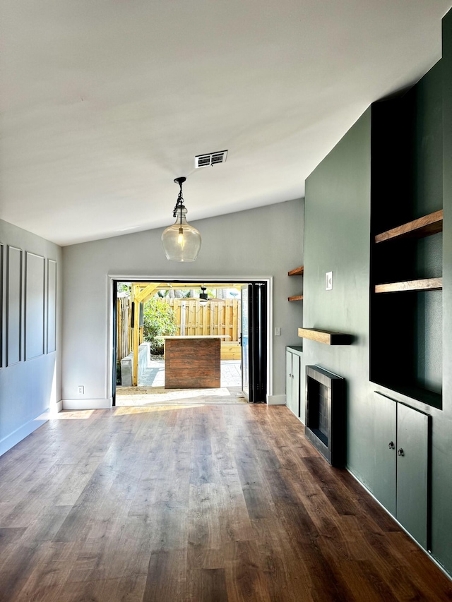 unfurnished living room featuring lofted ceiling, a fireplace, wood finished floors, and visible vents