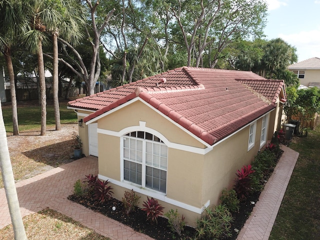 view of home's exterior with a tile roof, fence, and stucco siding