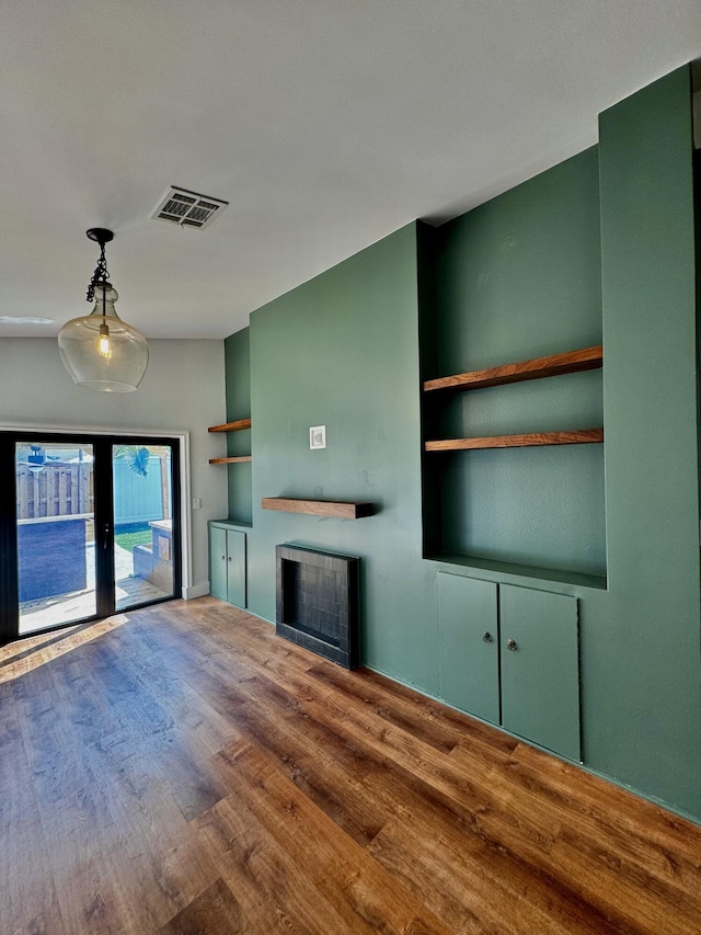 unfurnished living room with a fireplace, visible vents, wood finished floors, and french doors