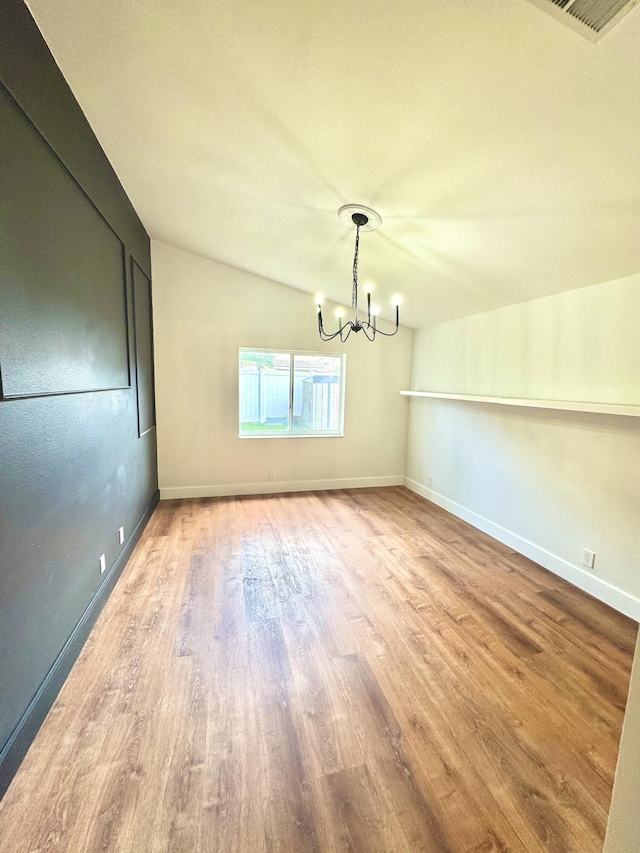 unfurnished room with baseboards, visible vents, a chandelier, and wood finished floors