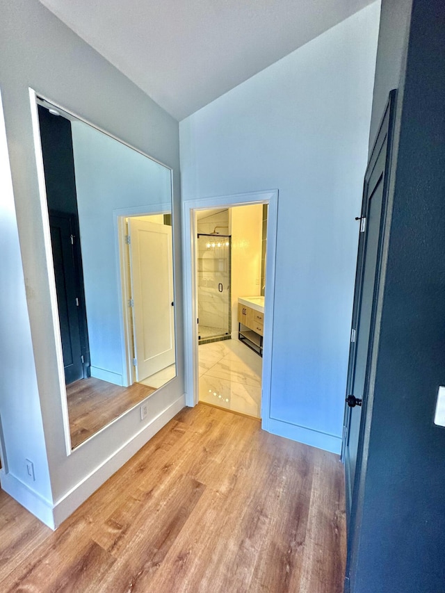 unfurnished bedroom featuring ensuite bath, light wood-style flooring, and baseboards