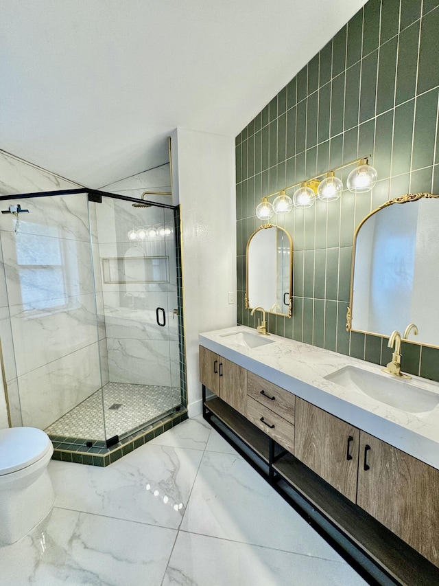 bathroom featuring marble finish floor, a shower stall, tile walls, and a sink