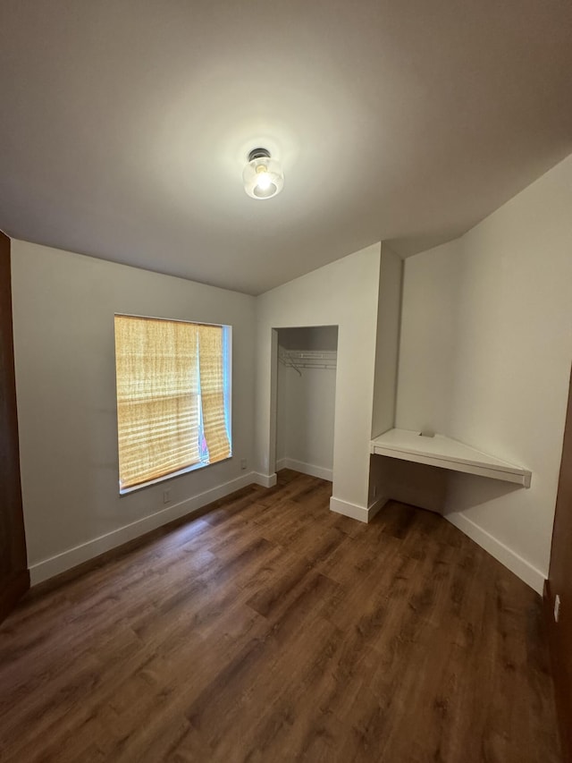 unfurnished bedroom featuring a closet, dark wood finished floors, and baseboards