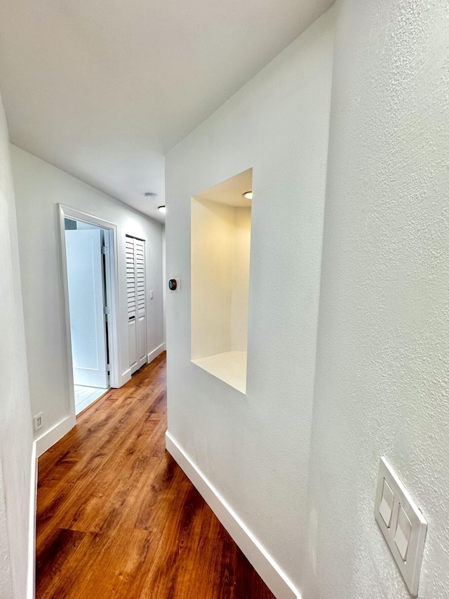 hallway featuring baseboards and wood finished floors