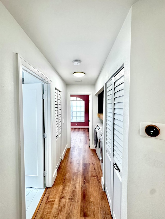 hallway featuring washer and clothes dryer, baseboards, and wood finished floors