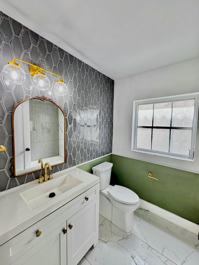 bathroom with toilet, marble finish floor, and vanity