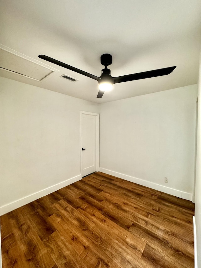 spare room featuring dark wood-style floors, visible vents, baseboards, and a ceiling fan