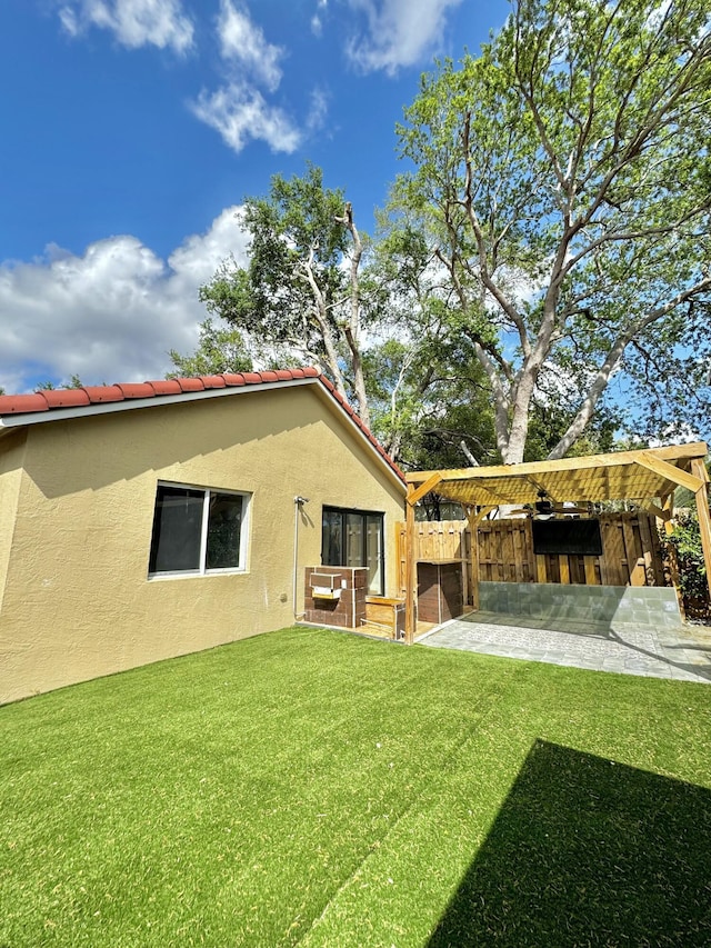 rear view of house featuring a patio area, a lawn, a tiled roof, and stucco siding