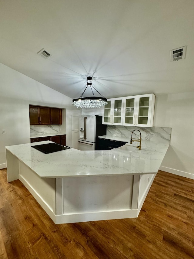 kitchen with a peninsula, light stone counters, visible vents, and decorative backsplash