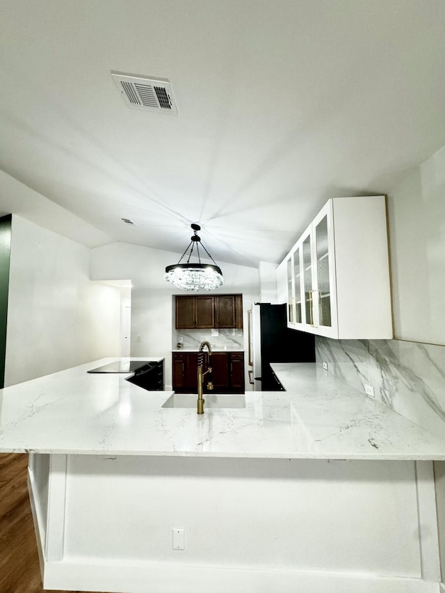 kitchen featuring freestanding refrigerator, glass insert cabinets, visible vents, and decorative backsplash