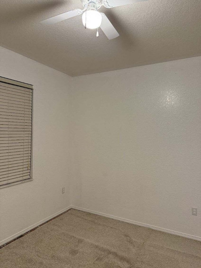 spare room with carpet floors, a ceiling fan, and a textured ceiling