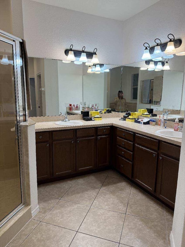 bathroom with double vanity, a stall shower, a sink, and tile patterned floors