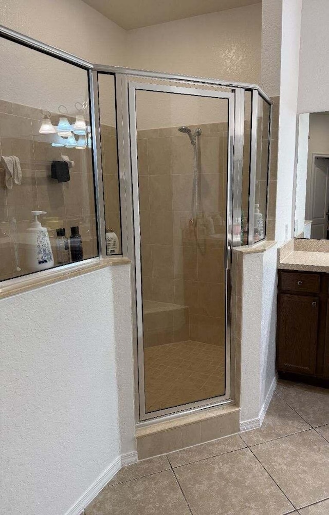 bathroom with baseboards, a shower stall, vanity, and tile patterned floors