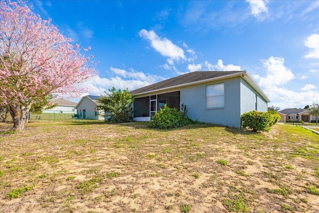 back of property featuring a lawn, a sunroom, and stucco siding