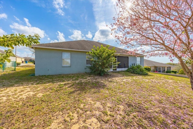 back of property featuring a yard, a sunroom, and stucco siding