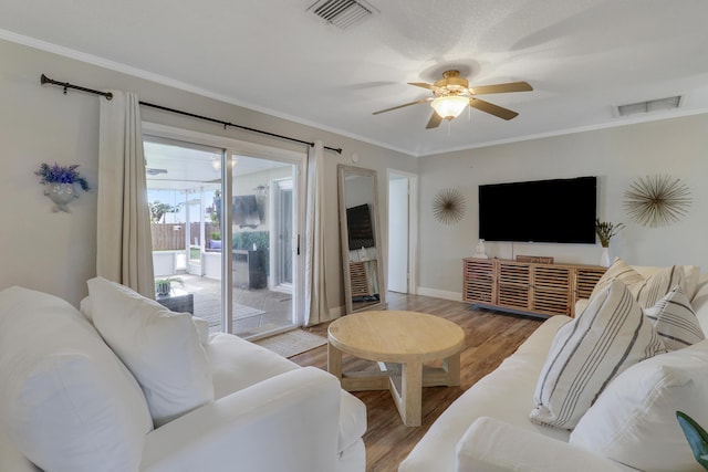 living area with light wood-type flooring, a ceiling fan, visible vents, and crown molding