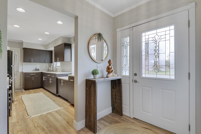 entryway featuring baseboards, ornamental molding, recessed lighting, and light wood-style floors