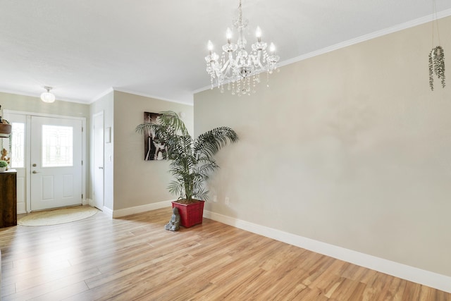 foyer entrance featuring ornamental molding, an inviting chandelier, baseboards, and wood finished floors