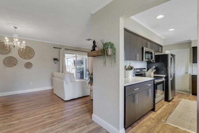 kitchen featuring baseboards, light countertops, appliances with stainless steel finishes, light wood finished floors, and crown molding