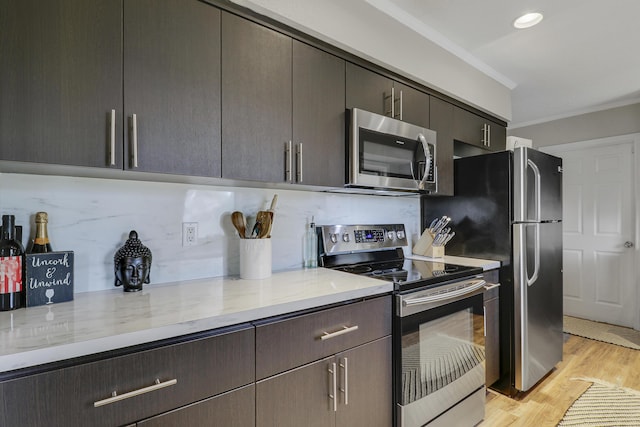 kitchen with light wood finished floors, decorative backsplash, light stone counters, appliances with stainless steel finishes, and crown molding