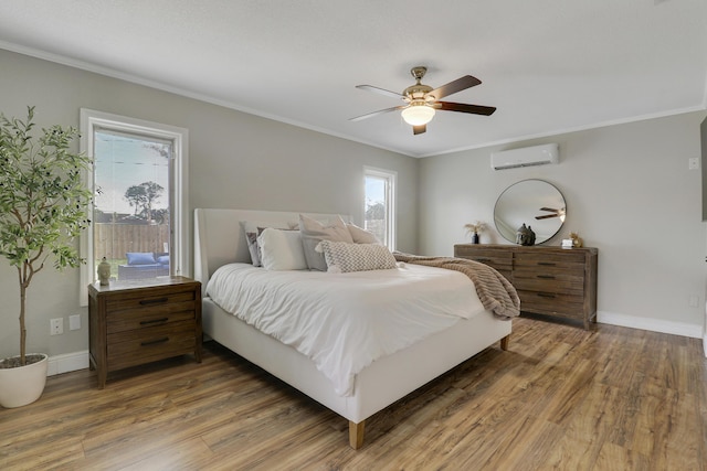 bedroom featuring a wall unit AC, light wood-type flooring, baseboards, and crown molding