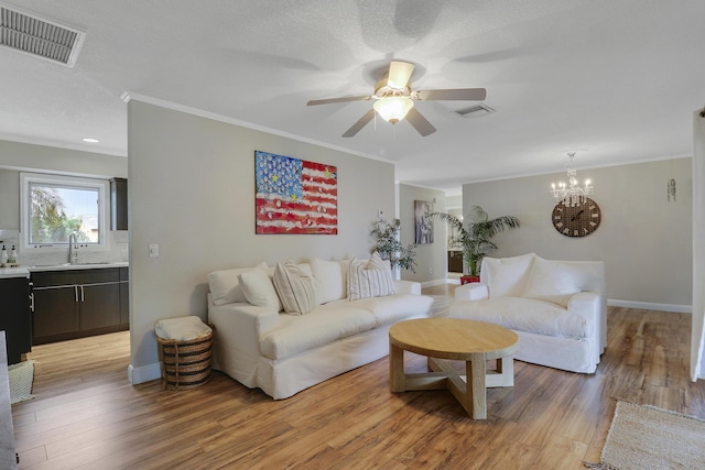 living area with baseboards, light wood finished floors, visible vents, and crown molding