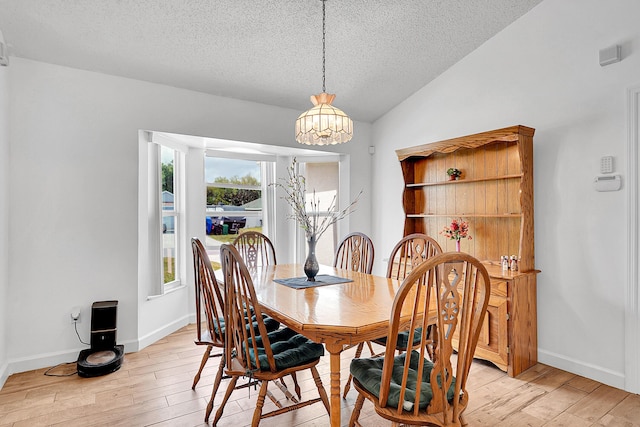 dining space with lofted ceiling, visible vents, light wood-style flooring, a textured ceiling, and baseboards