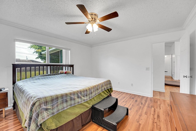 bedroom with a textured ceiling, baseboards, light wood-style flooring, and crown molding