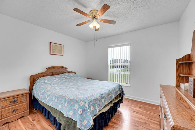 bedroom with a ceiling fan, light wood-type flooring, a textured ceiling, and baseboards