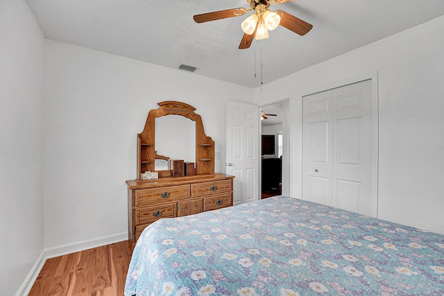 bedroom featuring a textured ceiling, wood finished floors, a ceiling fan, visible vents, and baseboards