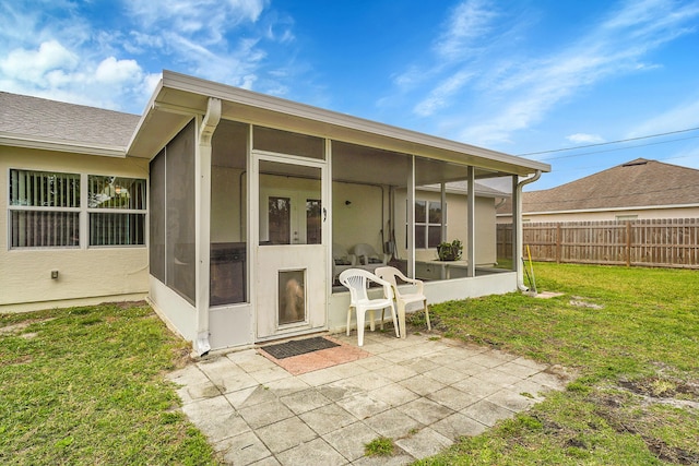 back of property featuring a sunroom, fence, a patio, and a lawn