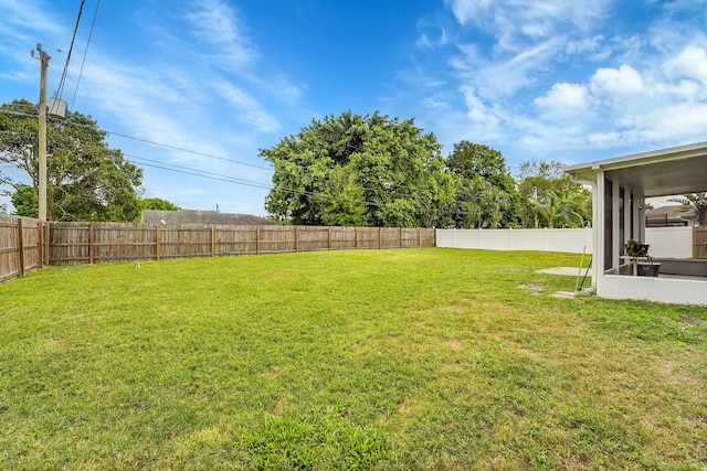 view of yard featuring a sunroom and a fenced backyard