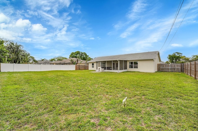 back of property featuring a sunroom, a fenced backyard, and a yard