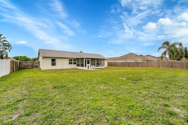 back of house featuring a sunroom, a fenced backyard, stucco siding, and a yard