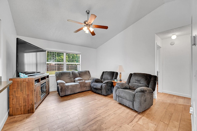 living room with vaulted ceiling, a textured ceiling, light wood-style flooring, and a ceiling fan