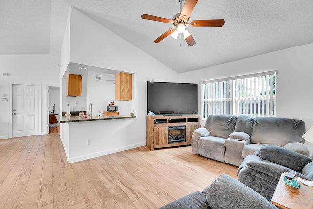 living room with a textured ceiling, ceiling fan, high vaulted ceiling, baseboards, and light wood finished floors