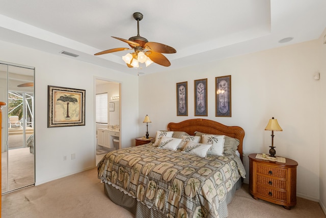 bedroom with light carpet, a raised ceiling, visible vents, and a ceiling fan