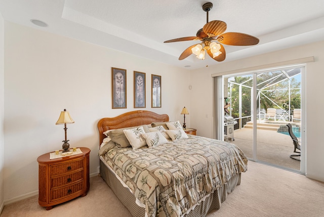 bedroom featuring access to outside, a tray ceiling, a ceiling fan, and light colored carpet