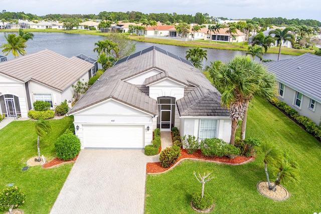 view of front of property featuring decorative driveway, a water view, a garage, a residential view, and a lanai