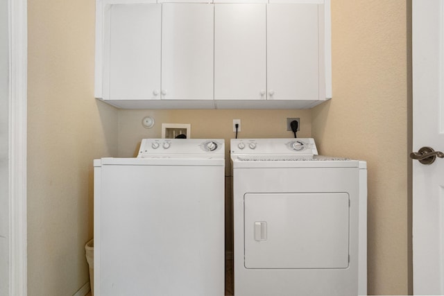 clothes washing area featuring washing machine and dryer and cabinet space