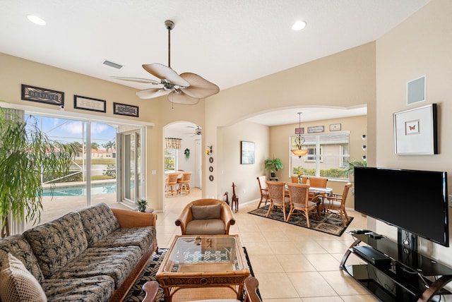 living room with light tile patterned floors, visible vents, arched walkways, and a ceiling fan