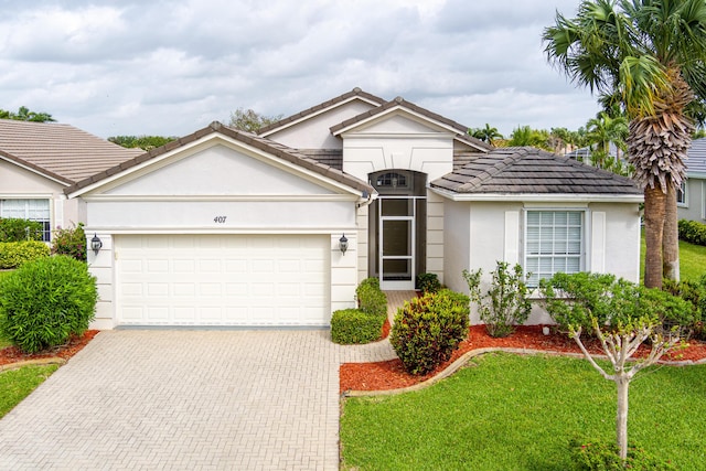 view of front of property featuring a garage, a tile roof, decorative driveway, a front lawn, and stucco siding