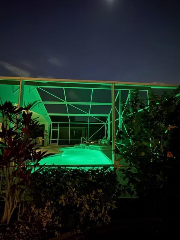 pool at night with a lanai and an outdoor pool