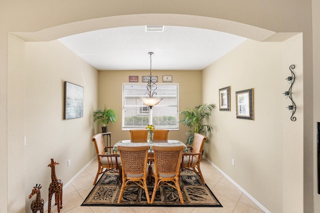 dining area with light tile patterned floors, baseboards, and arched walkways