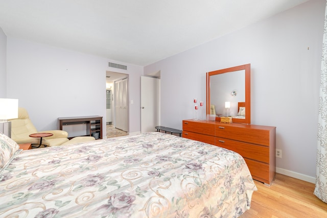 bedroom featuring light wood-style floors, visible vents, and baseboards