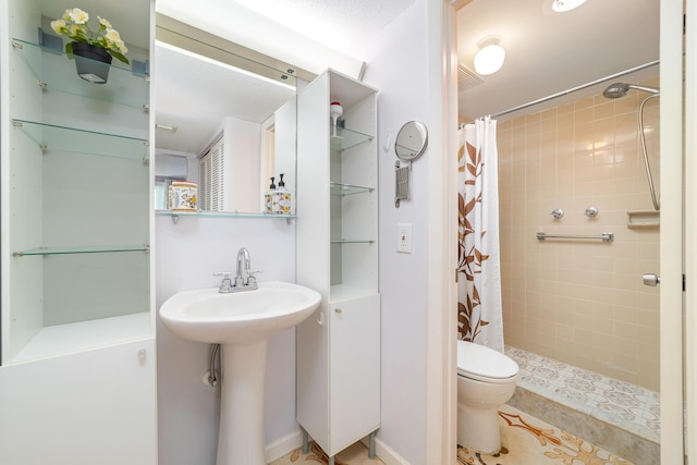 bathroom featuring a sink, toilet, a tile shower, and visible vents