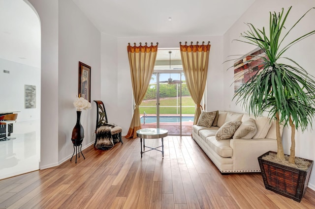 living area featuring light wood-type flooring, baseboards, and arched walkways