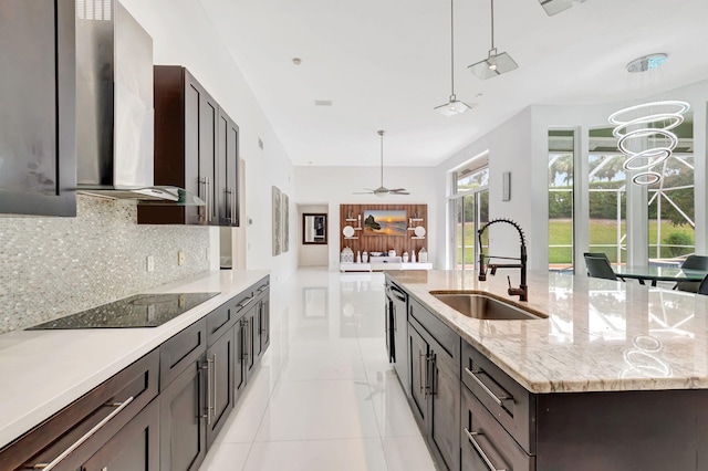 kitchen featuring black electric stovetop, backsplash, a sink, a large island with sink, and wall chimney exhaust hood